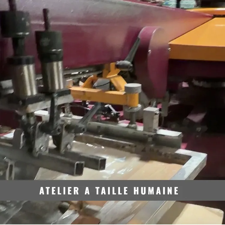 Machine de sérigraphie en fonctionnement dans un atelier de marquage textile à taille humaine.