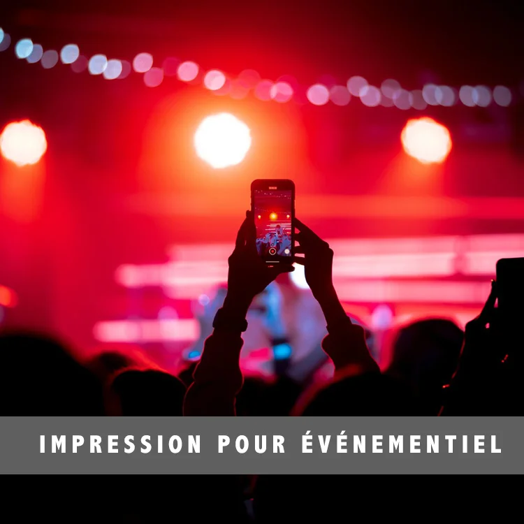 Public assistant à un événement, filmant une scène avec un smartphone, illustrant des solutions textiles personnalisées pour l'événementiel.